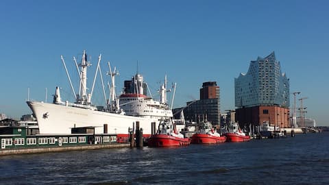 Hafenszene mit altem weissem Frachter und 3 roten Schleppern, im Hintergrund die Elbphilharmnie