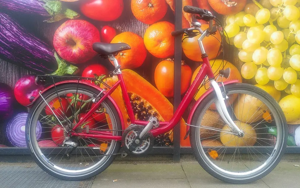 Rote Damenfahrrad vor einer Fotowand mit frischem bunten Obst